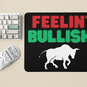 A desktop setup with a Feelin' Bullish Mouse Pad - Unleash Your Market Confidence embodying market confidence, featuring a silhouette of a bull, next to a white keyboard and mouse, demonstrates a confident and positive attitude.